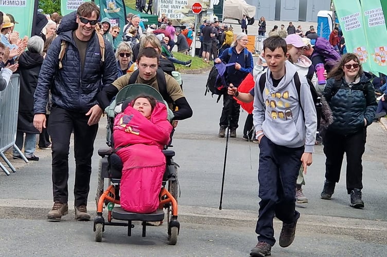 Damien Bowyer, 17, of Tavistock, is pictured left pushing a fellow hiker across the finish line at Okehampton Army Camp at the Ten Tors Jubilee Challenge.