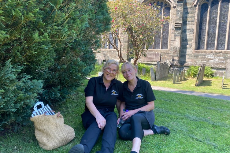 Two colleagues cool off in the shade of a St Eustachius' Church yew after a shift in the Original Pasty House in Tavistock.