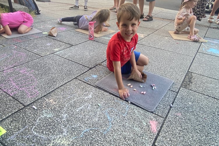 Young artists decorating Tavistock high street for the Lions Carnival Week pavement art competition.