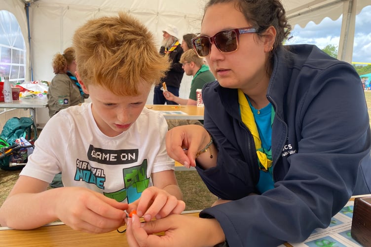 Buckland and Horrabridge Cub Harry is shown how to make a para-cord person by a Walkham Valley Scout Group leader at Yelverton Rotary Club free family fun day.