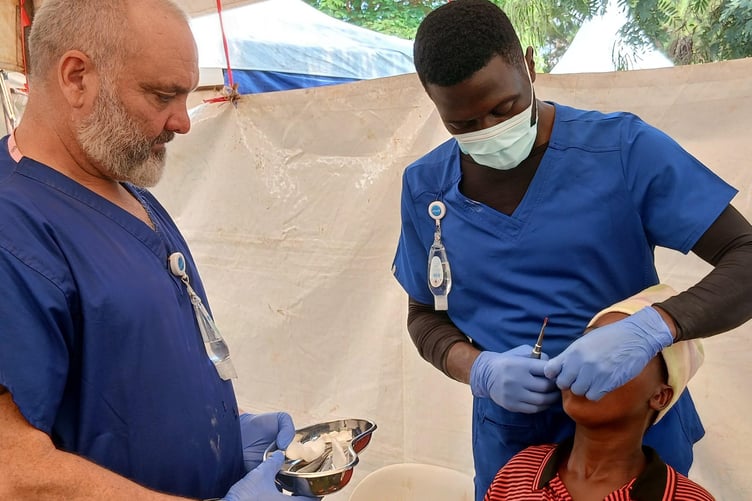 Lee Spencer, of Horrabridge, supports a dentist during a charity village dental clinic in Uganda.